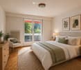 Cozy bedroom with a large bed, nightstands, a chair, a mirror, a small table, and decorative items including lamps, picture frames, and plants.