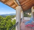Balcony with wooden ceiling, tiled floor, and two lounge chairs, overlooking a scenic mountain view.