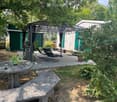 Outdoor patio area with a covered seating area, lounge chairs, a stone table, and surrounding greenery.