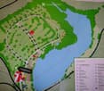 A detailed map of a recreational area, showing pathways, parking, mobile homes, and various facilities including a lake, playground, and sanitary facilities.