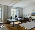 modern office room with two desks, monitors, office chairs, bookshelves, floor lamp, window