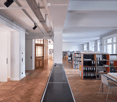 wooden parquet flooring, long rectangular counter, white walls, bookshelves, windows with wooden frames, desk with objects on top