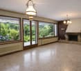 Unfurnished Room. Empty living room with large windows, tiled floor, fireplace, and radiators. No furniture present.