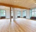 Unfurnished Room. Completely empty room with wooden floor, white walls, large windows, and exposed wooden beams on the ceiling.