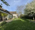 Garden / Outdoor Area. Well-maintained garden with a paved pathway, lawn, and a small seating area with a table and chairs near the house.