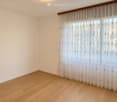 Unfurnished Room. Empty room with light wooden flooring and white walls, featuring a large window with sheer curtains.