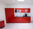 Kitchen. Modern kitchen with red cabinets, a sink, a faucet, and a coffee maker on the counter.