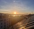 Balcony / Terrace. Roof terrace view overlooking a cityscape at sunset, with buildings, cranes, and a body of water in the distance.