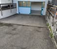 Garage with two doors, concrete floor, wall with windows, parked camper van