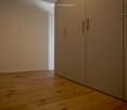 Unfurnished Room. Empty hallway with wooden flooring and light-colored walls, featuring a set of closed double doors on the right side.