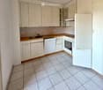 Modern kitchen with light-colored cabinets, tiled floor, and built-in appliances including a refrigerator, oven, and dishwasher.