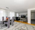 Furnished Room. A modern living and dining area with a glass dining table, purple chairs, a sofa, a television, and a patterned rug.