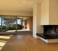 Living Room. Modern living room with light wooden flooring, large glass doors leading to a patio, and a built-in fireplace.