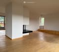 Unfurnished Room. Empty room with light wooden flooring, white walls, and large windows allowing natural light. Features a fireplace and a built-in bench along one wall.