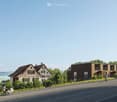 Building. A modern residential complex with a mix of contemporary and traditional-style buildings, surrounded by greenery and a clear view of a lake in the background.