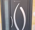 Corridor / Hallway. Modern grey front door with glass panels and sleek silver handle design.