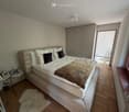 Bedroom. Modern bedroom with a large bed, nightstand, mirror, wardrobe, and a small table with picture frames.