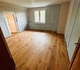 Empty room with wooden flooring, white walls, and a window with a radiator below it. No furniture or equipment is present.