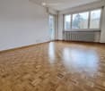 Unfurnished Room. Empty room with wooden parquet flooring, white walls, large windows, and a radiator under the windows.