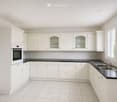 Bright, modern kitchen with white cabinets, black countertops, and a stainless steel sink.