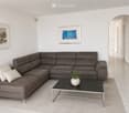 Modern living room with a grey sectional sofa, white throw pillows, a black coffee table with a small potted plant, and two framed artworks on the wall.