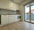 Kitchen. Modern kitchen with white cabinets, tiled backsplash, granite countertop, and an open sliding door leading to a balcony.