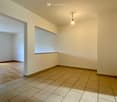 Unfurnished Room. Empty room with tiled floor and white walls, featuring a single hanging light fixture and an open doorway leading to another space.