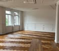 Unfurnished Room. Empty room with wooden herringbone flooring, white walls, large windows, and decorative ceiling moldings.