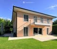 House. Two-story house with light pink exterior, white-framed windows, and a balcony on the upper level. Features a well-maintained lawn, patio area, and outdoor furniture.
