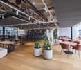 Furnished Room. Modern restaurant or lounge area with wooden flooring, white tables, pink chairs, and potted plants.