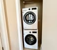 Bathroom. A small, well-lit laundry area with a stacked washer and dryer unit against the wall.