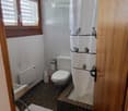 Bathroom with a toilet, shower curtain featuring birds, bathtub, radiator, and a bath mat on the floor.