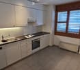 Modern kitchen with white cabinets, stainless steel sink, oven, and countertop. Features a window with blinds and built-in lighting under the cabinets.