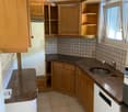 Compact kitchen with wooden cabinets, granite countertops, electric stove, sink, and refrigerator.