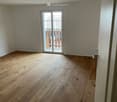 Empty room with wooden flooring and a sliding glass door leading to a balcony.