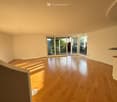 Empty room with wooden flooring, large sliding glass doors leading to an outdoor area, and natural light streaming in.