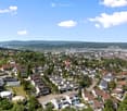 dense urban area, multiple houses, hills in the background, some houses with garages