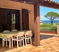 Outdoor patio with a table and chairs, overlooking the sea and a tree-lined coastline.