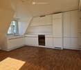 Modern kitchen with white cabinets, wooden flooring, and a built-in oven. Features a window with blinds and a sleek sink area.