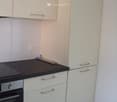Modern kitchen with white cabinets, black countertop, and built-in oven.