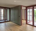 Empty room with wooden flooring, large sliding glass doors leading to a balcony, and neutral-colored walls.