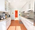 Modern kitchen with white cabinets, granite countertops, stainless steel appliances, and a visible doorway leading to another room.