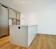 Modern kitchen with white cabinetry, a central island, and a stainless steel sink with a modern faucet. The floor is made of light wood.