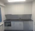 Modern kitchen with white cabinets, black countertops, stainless steel sink, oven, and dishwasher.
