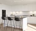 Modern kitchen with white cabinets, black countertop, island with bar stools, sink, oven, and small decorative items.