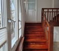Wooden staircase with a handrail and a frosted glass door at the end of the hallway.