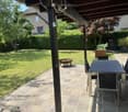 Patio area with tiled floor, outdoor dining table and chairs, fire pit, and well-maintained lawn.
