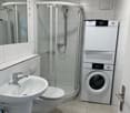 modern bathroom with shower, toilet, sink, washing machine, and dryer