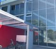 Modern building with glass walls, red wall, glass door, bicycle parking, entrance