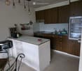 Modern kitchen with wooden cabinets, stainless steel appliances, island, and seating area.
